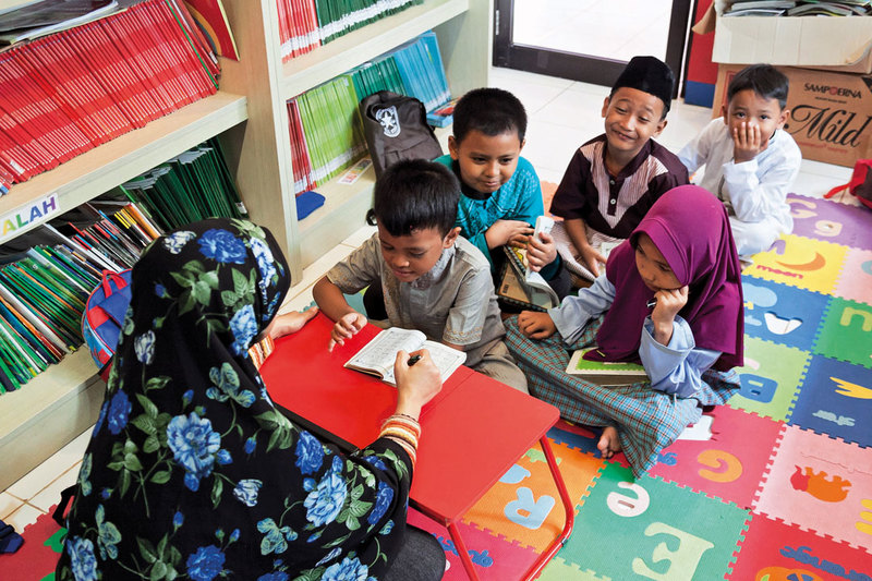 Children lining up to learn reading the Koran with one female teacher at Taman Sawo Family Park, South Jakarta.