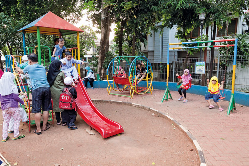 Parents accompanying their children playing in the children playground at Taman Sawo Family Park, South Jakarta