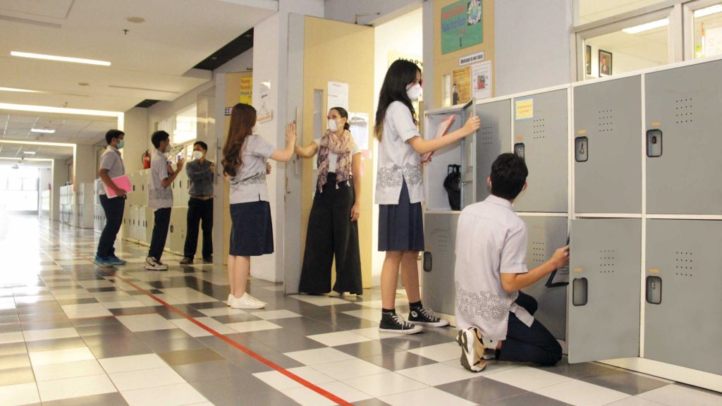 highscope indonesia students are seen opening their lockers in one of the school's hallways. A teacher high fives